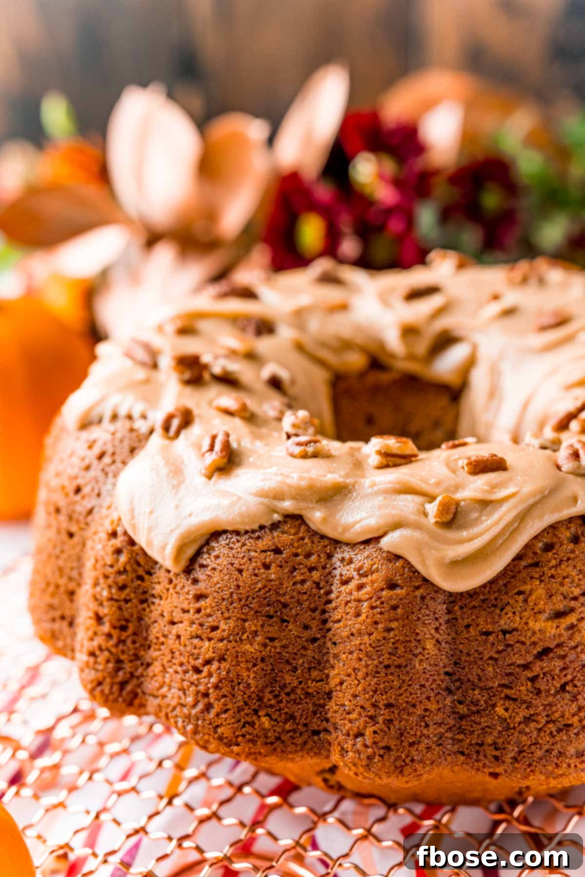 Close up photo of an iced pumpkin bundt cake on a gold wire rack.