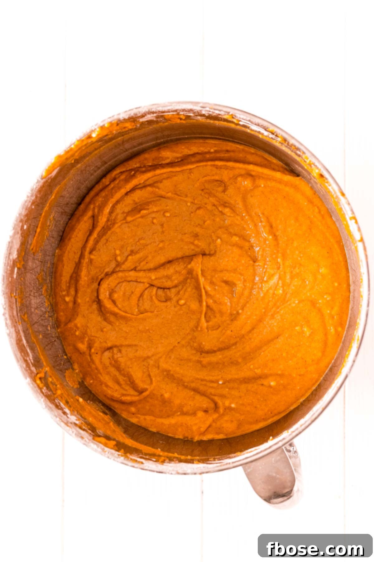 Overhead photo of pumpkin cake batter in a stainless steel mixing bowl.