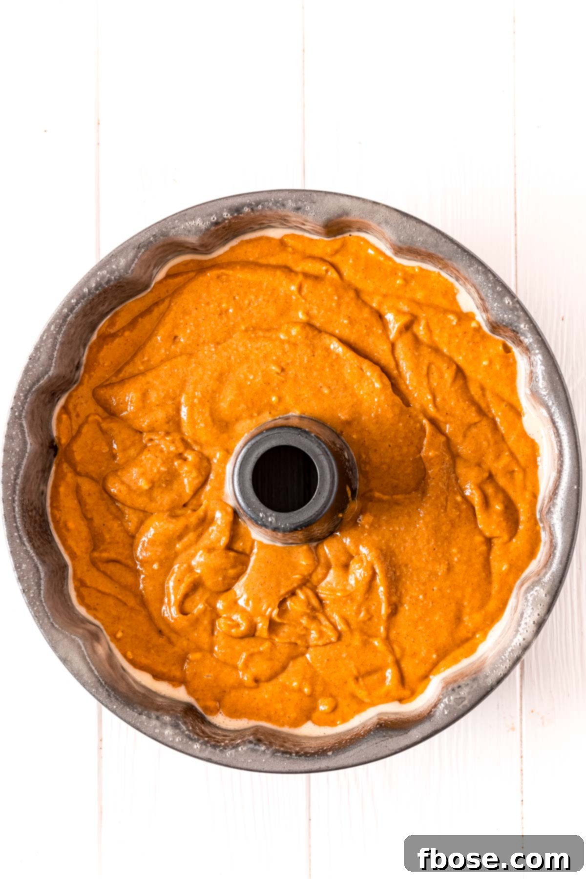 A bundt cake pan filled with pumpkin cake batter ready to bake.