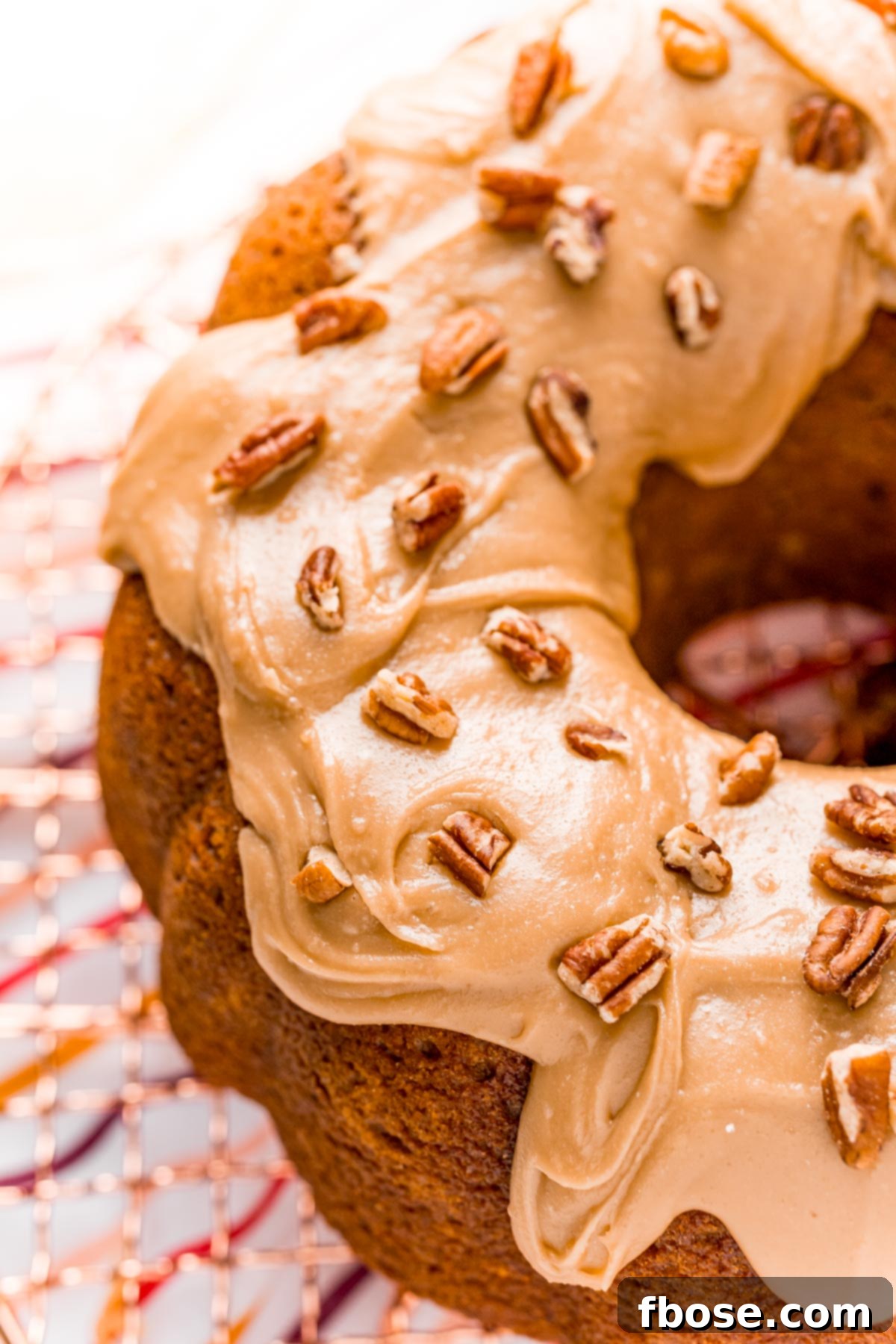Close up photo of a pumpkin pound cake with icing on it topped with pecans.