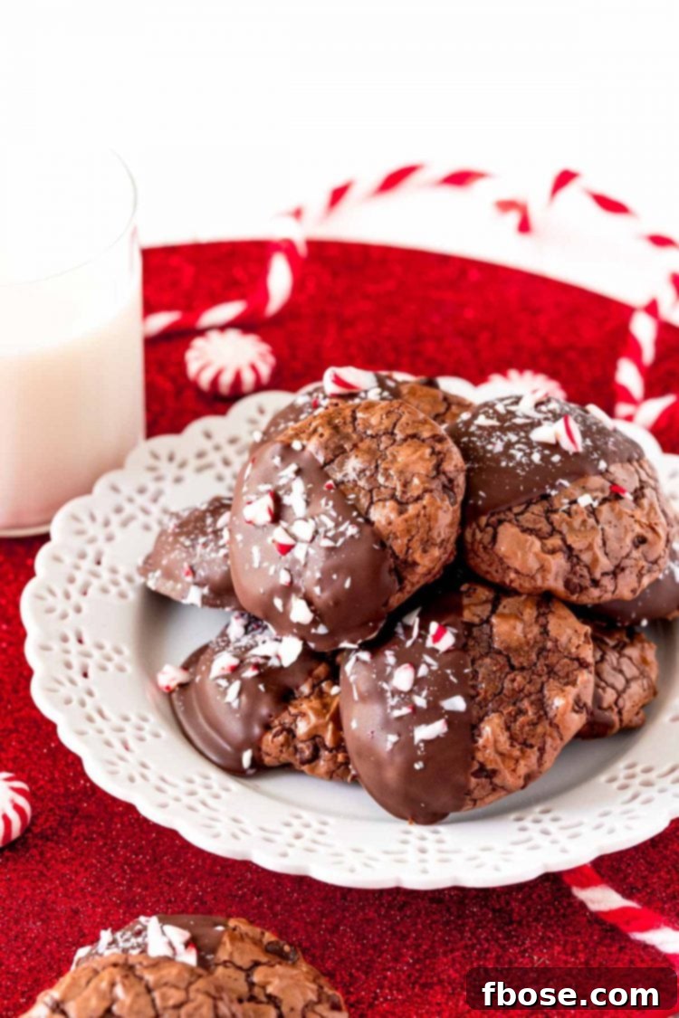 Peppermint chocolate cookies on a white plate with a glass of milk next to it, inviting a delicious treat.
