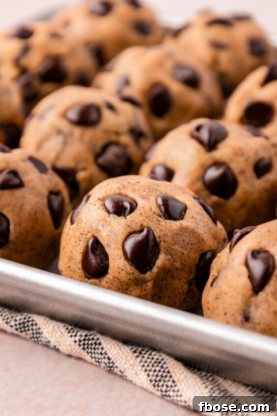 Close up of chocolate chip cookie dough balls on a sheet pan.