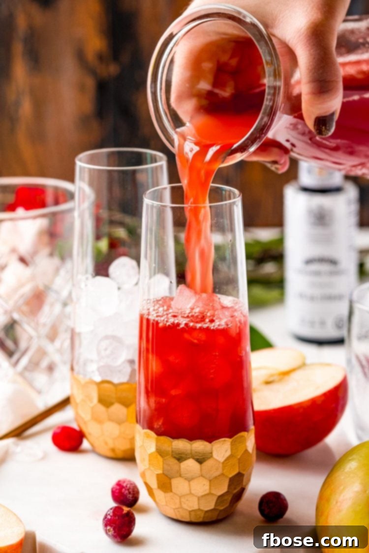 Ruby Red Apple Cider Punch 5 Sparkling cranberry punch being poured into an individual serving glass over ice.