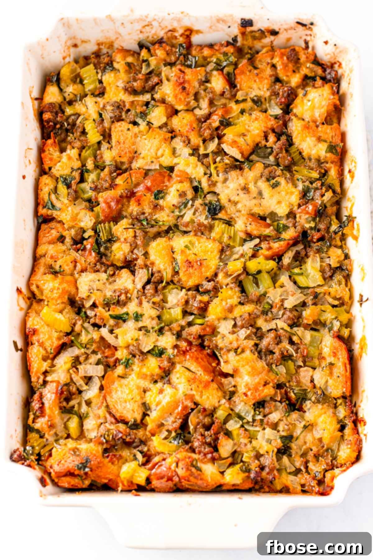 Ultimate Sausage Stuffing 3 Close up photo of savory Thanksgiving dressing with sausage in a white baking dish.