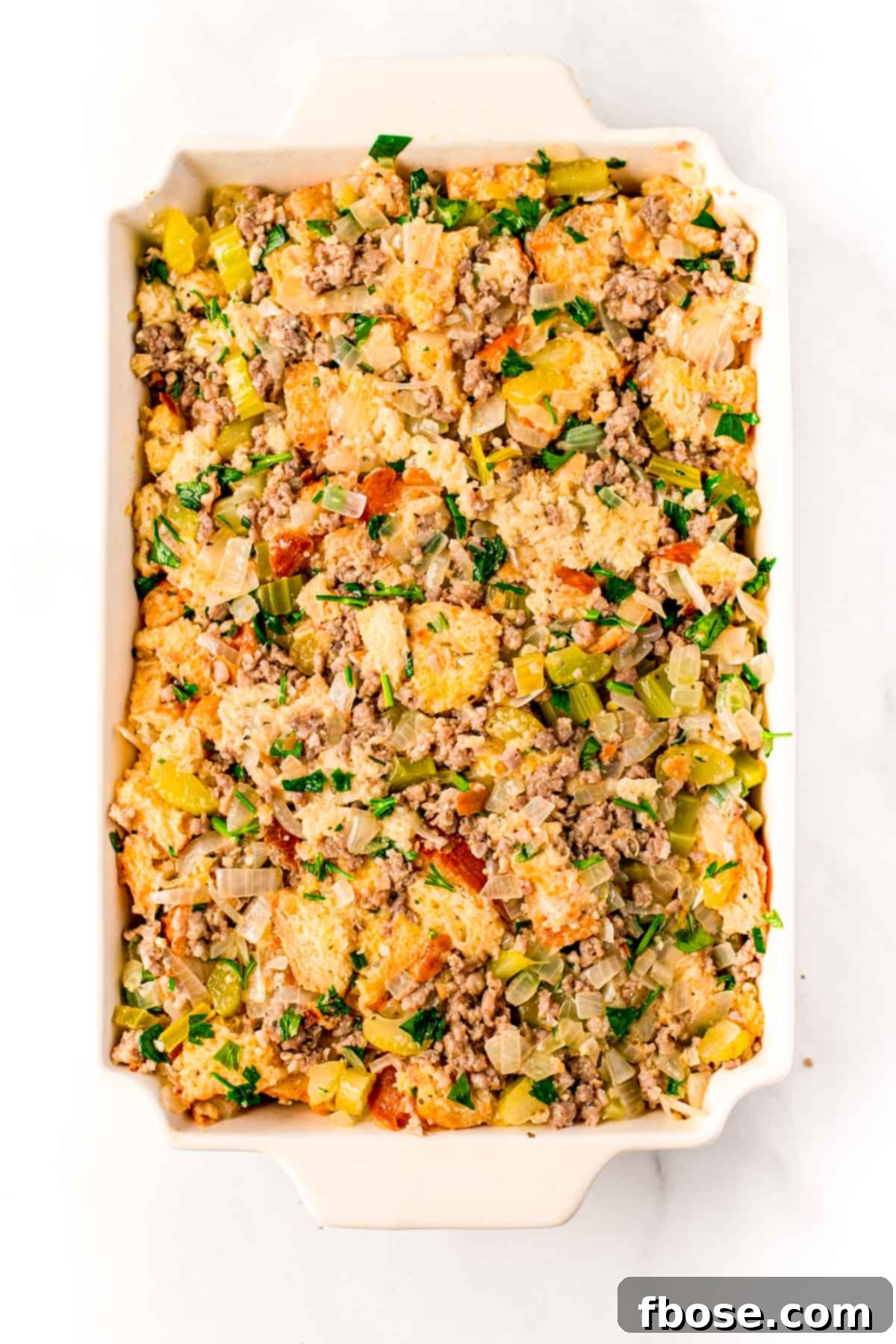 Ultimate Sausage Stuffing 7 Overhead photo of a casserole dish filled with unbaked sausage stuffing mixture, perfectly pressed and ready to be transferred into the oven for baking.