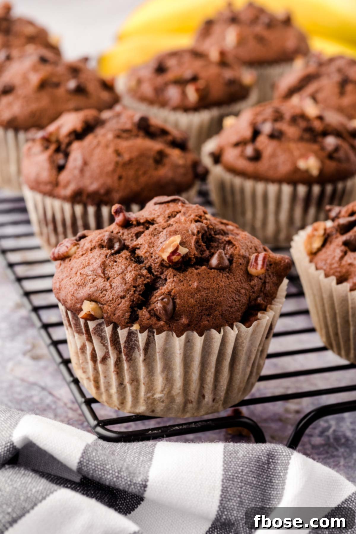 Freshly baked Chocolate Chip Banana Pecan Muffins cooling on a wire rack, ready to be enjoyed.