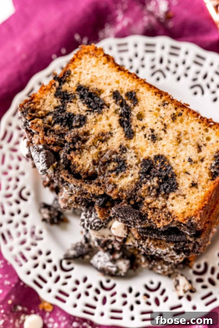 A whole Oreo Crumb Cake, still warm on a white plate, positioned on a purple napkin, ready for serving.