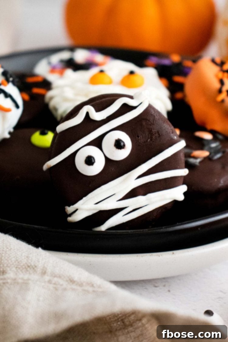 Close up photo of Halloween decorate oreos on a black plate.