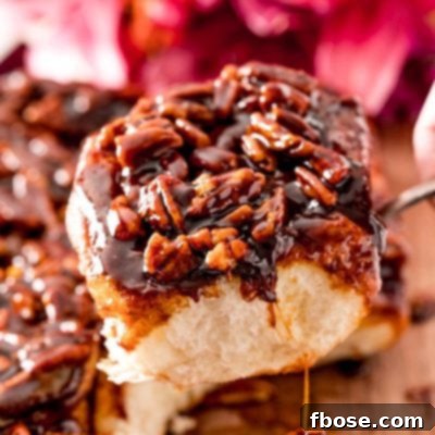 Close up photo of a pecan sticky bun being pulled away from the rest on a serving spoon.