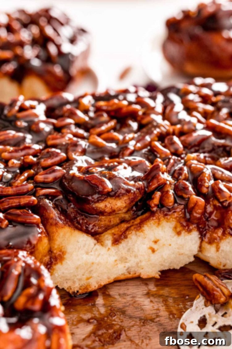 Close up photo of sticky buns fresh from the pan, with one bun expertly taken out to showcase its gooey bottom.