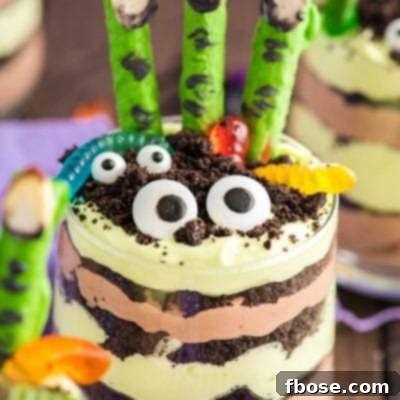 Close up photo of layers Halloween dirt cups with pretzel stick witch fingers, candy eyes, and gummy worms.