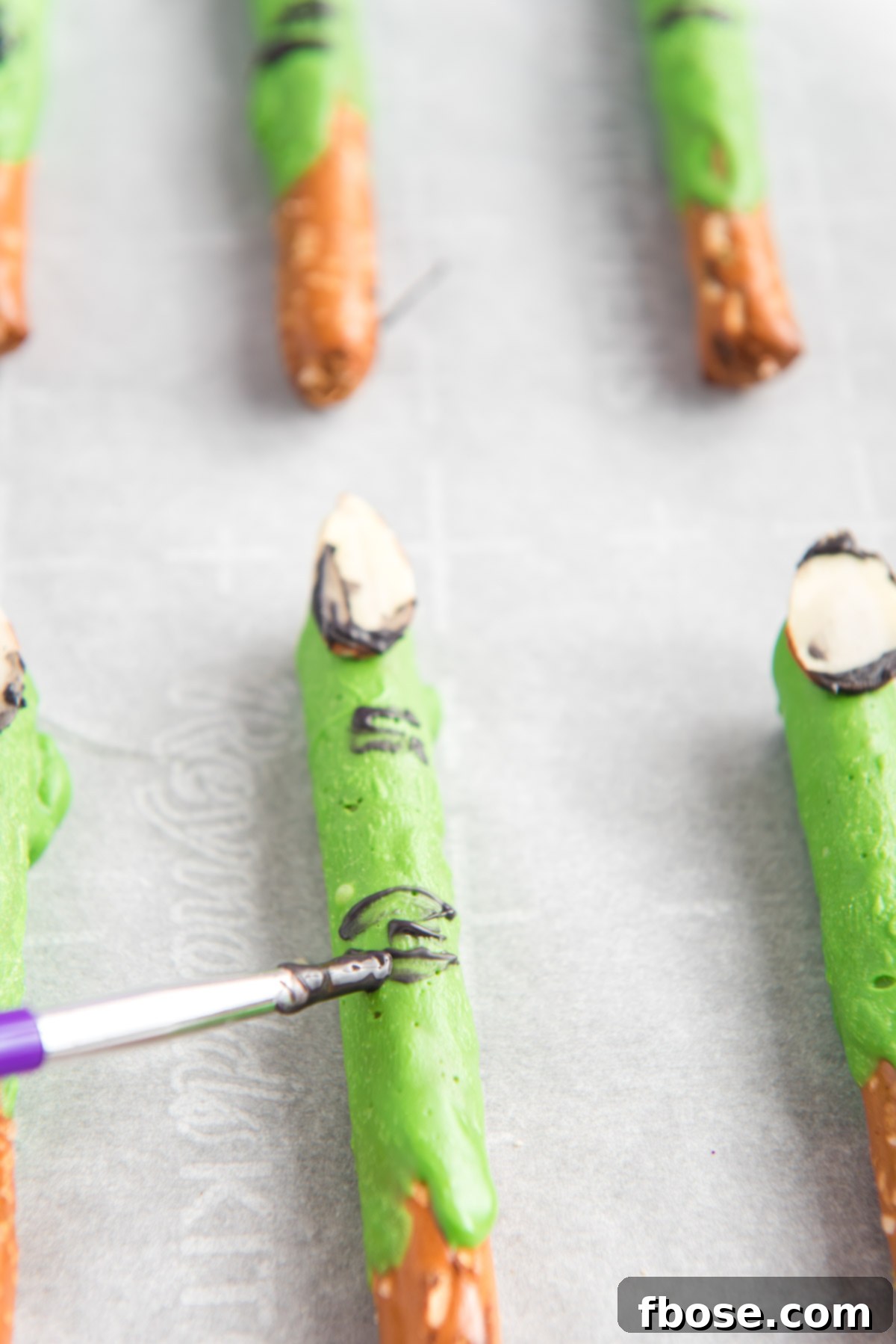 Witch finger pretzel rods being painted.