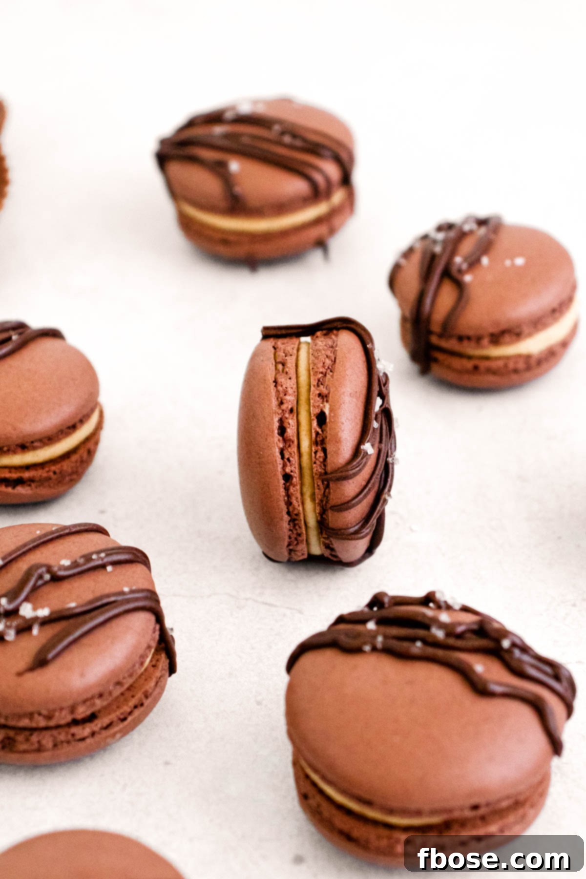 Close up of of peanut butter chocolate macarons on a white counter.