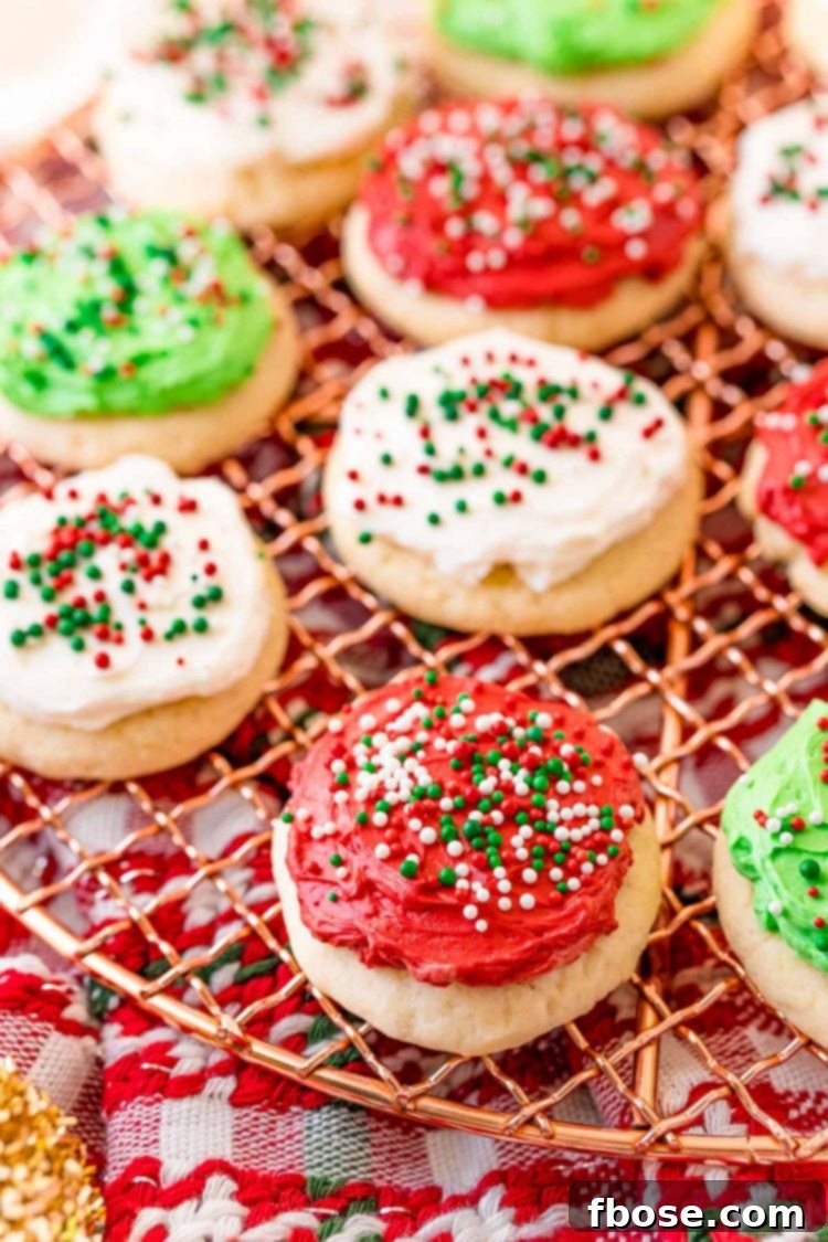 A delightful array of red, white, and green frosted sugar cookies, generously covered in sprinkles, resting on a wire cooling rack, ready for the holidays.