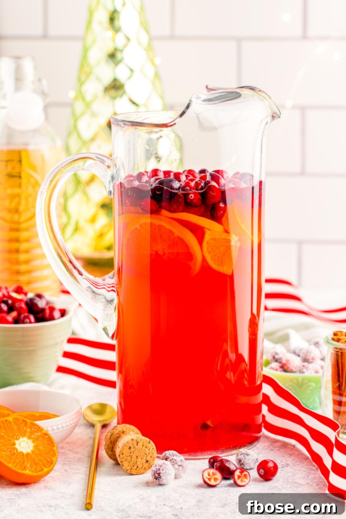 Crimson & Citrus Yuletide Sparkler 2 A pitcher of Christmas Mimosa Punch, garnished with fresh cranberries and orange slices, ready to be served at a holiday event.