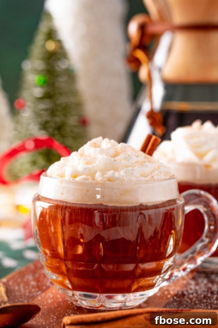 Close-up photo of a steaming mug of hot Christmas spiced coffee, topped with fluffy whipped cream and a sprinkle of cinnamon, set against a festive holiday backdrop.