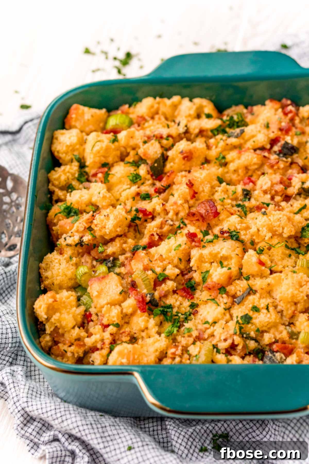 The Ultimate Cornbread Dressing 2 Golden brown Southern Cornbread Dressing in a beautiful teal baking dish, ready to be served at a holiday gathering.