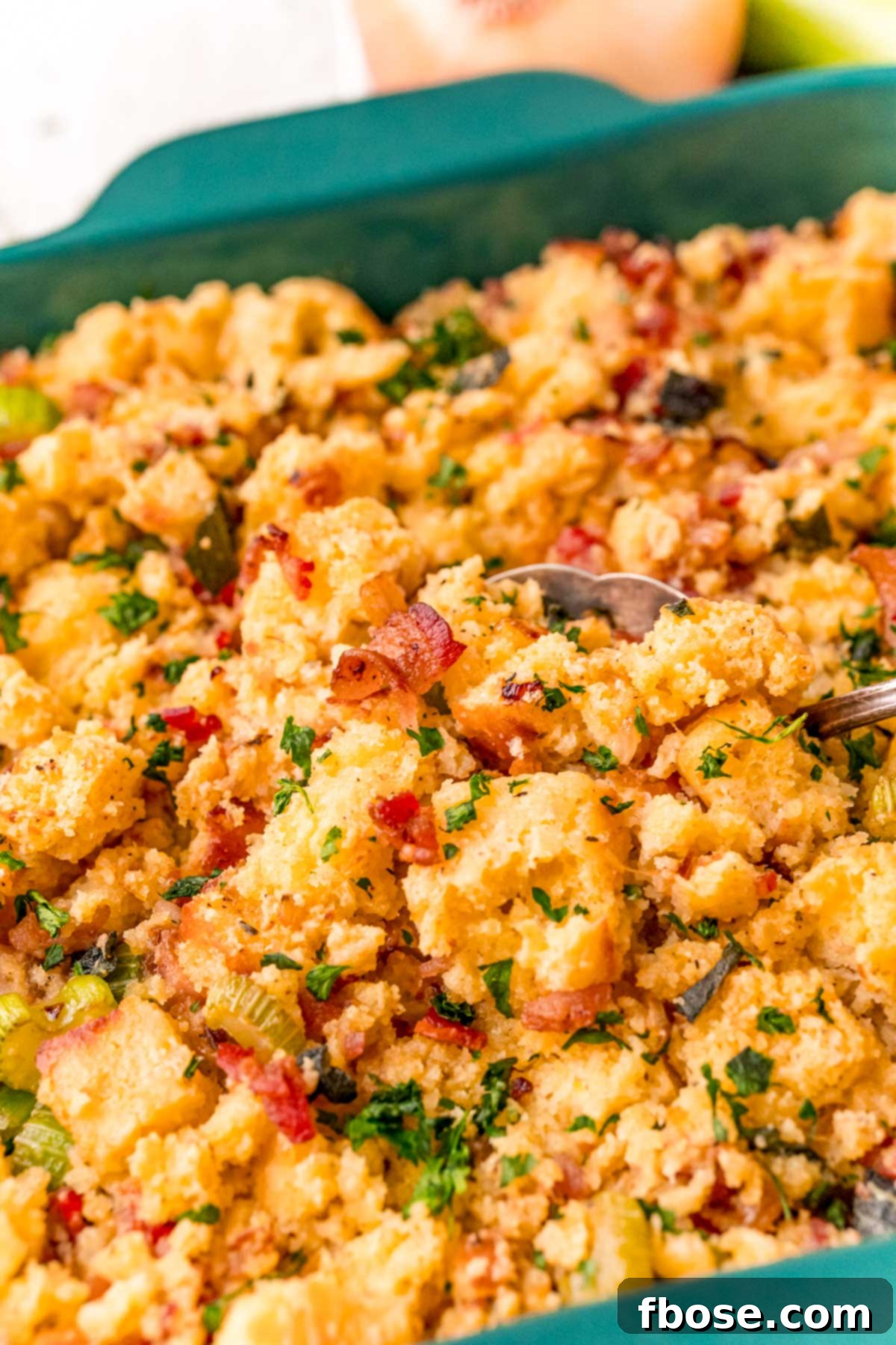 The Ultimate Cornbread Dressing 3 Close-up of fluffy, golden cornbread stuffing being scooped from a baking dish, highlighting its delightful texture.