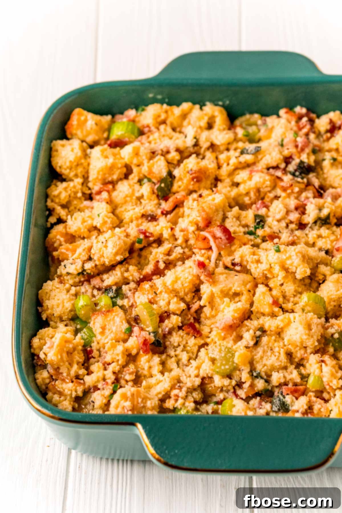 The Ultimate Cornbread Dressing 7 The savory cornbread stuffing mixture carefully placed in a teal baking dish, ready for its final bake.