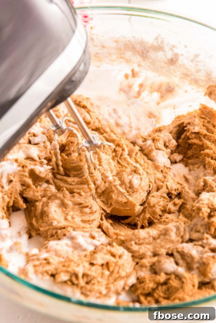 Zencefilli Sandviç Kurabiye, Kahverengi Şeker Kremalı 7 Cake batter being mixed in a glass mixing bowl with a hand mixer.