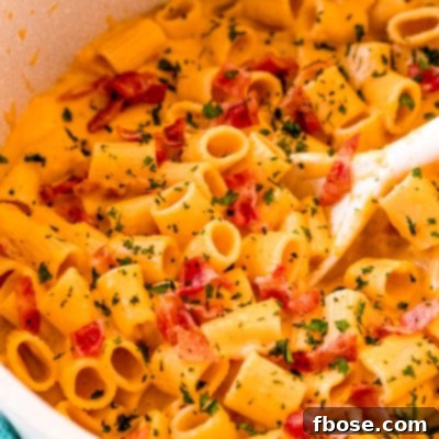 Butternut squash mac and cheese in a pot with a white serving spoon.