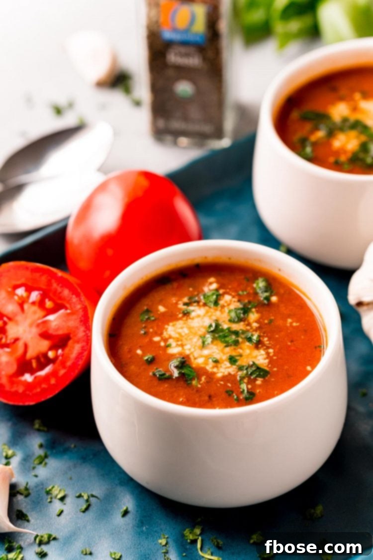 Tomato soup in a white bowl on a blue serving tray.
