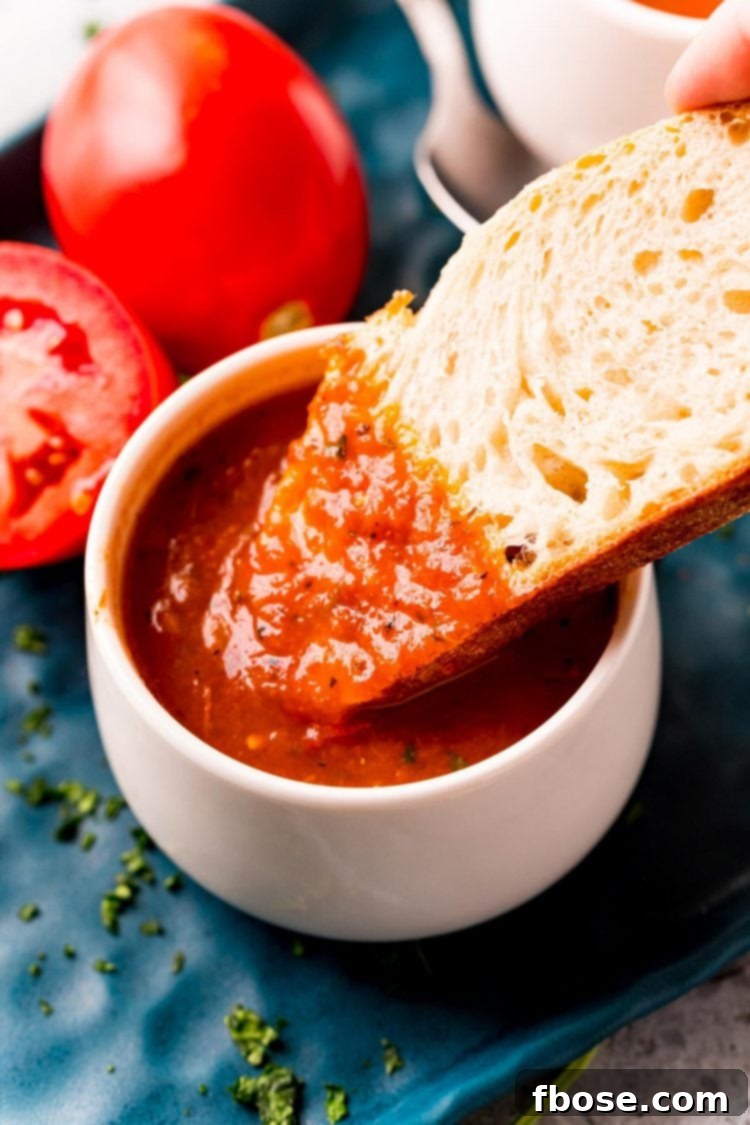 A slice of bread being dipped in tomato soup.