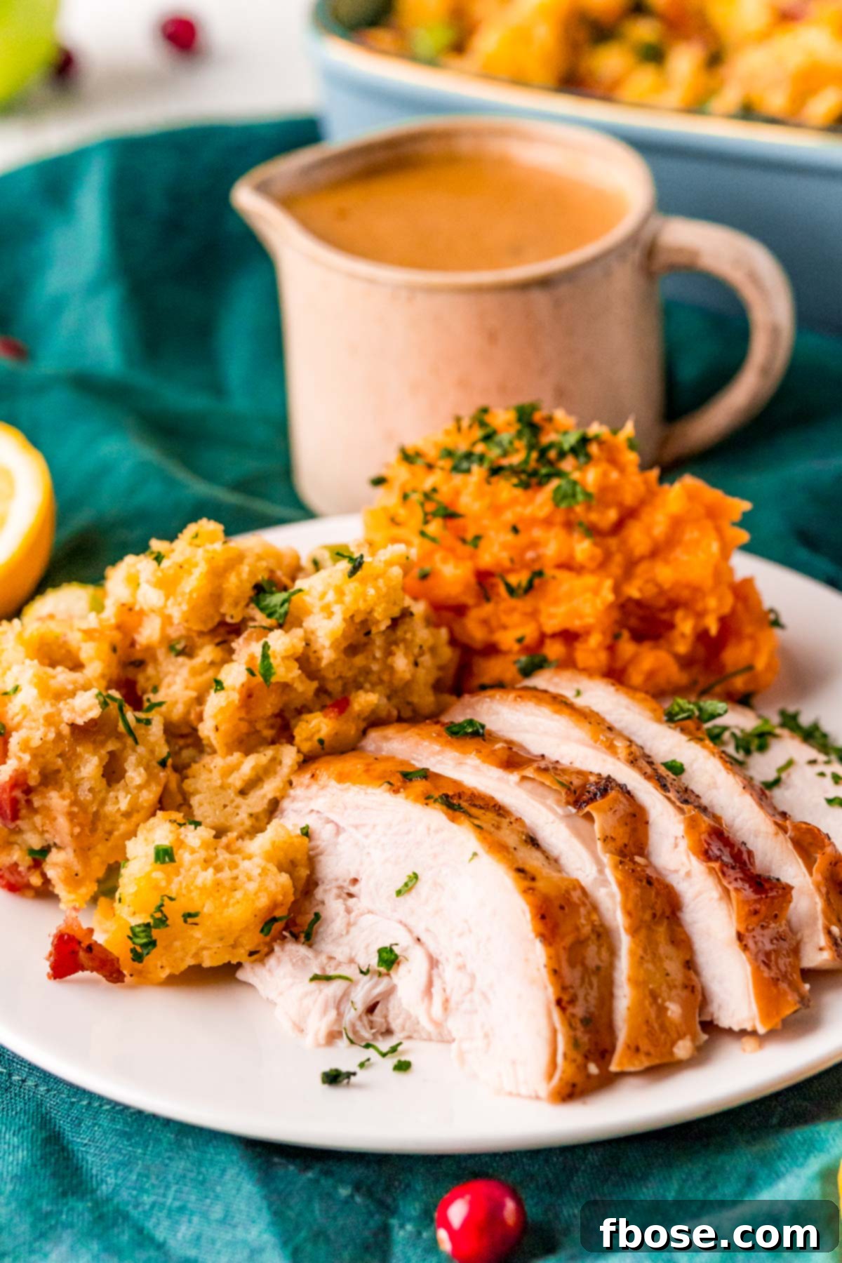 Close-up photo of perfectly sliced turkey breast arranged on a plate, accompanied by creamy mashed sweet potatoes and savory stuffing.