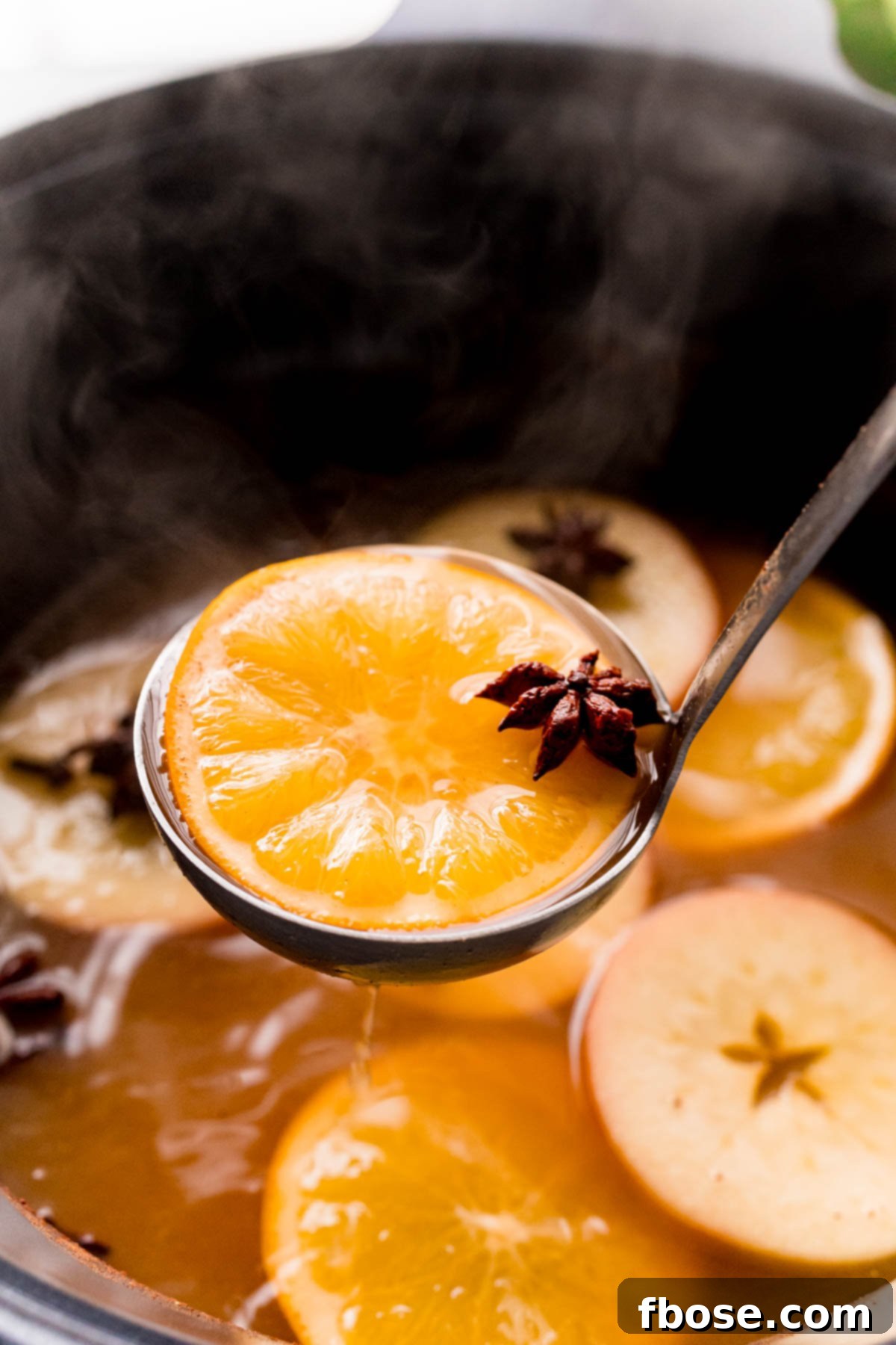 A ladle scooping wassail out of a crockpot.