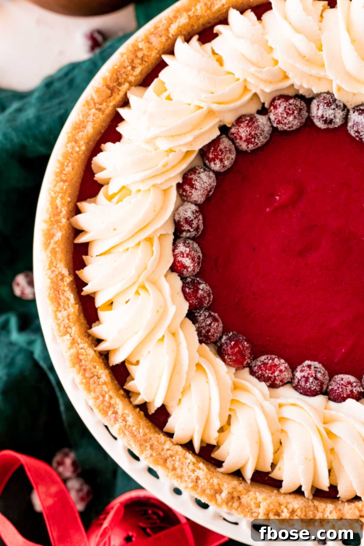 Overhead photo of a fully assembled cranberry pie, adorned with swirls of whipped cream and sparkling sugared cranberries, ready to serve.