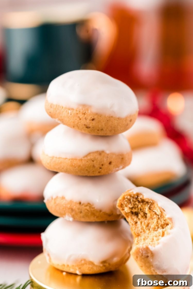 Stack of 4 pfeffernusse cookies with one cookie with a bite taken out of it leaning against the stack.