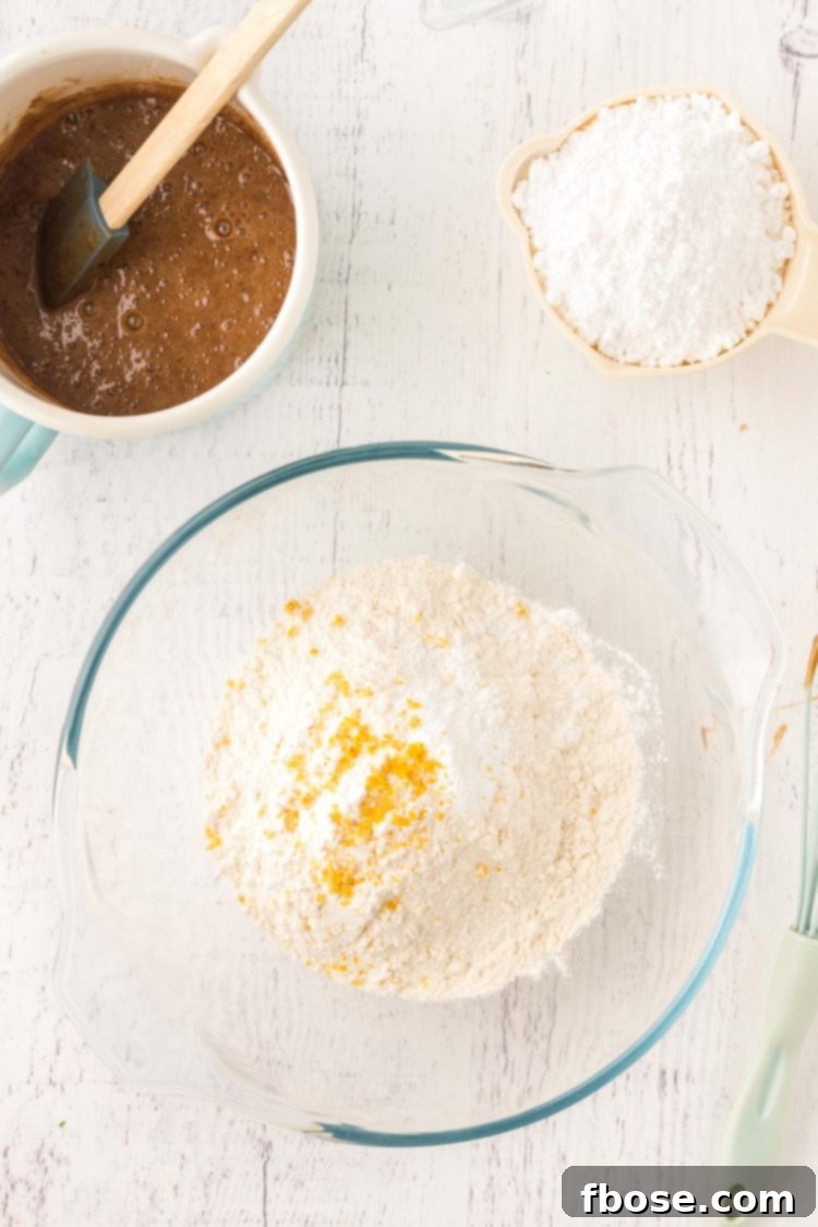 Overhead photo of a glass mixing bowl with flour and lemon zest in it.