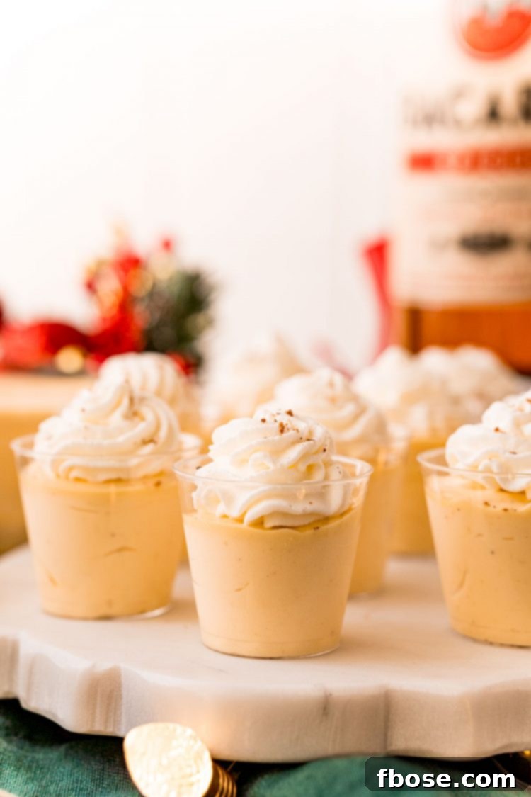Close up photo of eggnog pudding shots on a white marble stand, garnished with nutmeg.