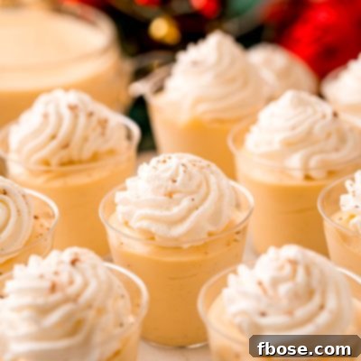 Close up photo of pudding shots topped with whipped cream and nutmeg.