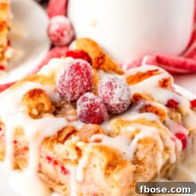 Close up photo of cranberry white chocolate bread pudding on a white plate, ready to be served.