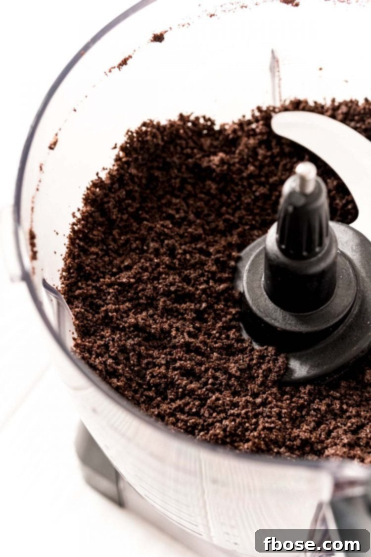 Finely crushed Oreo crumbs, ready for mixing, visible inside a food processor.