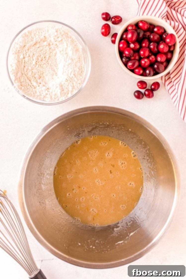Overhead photo of a metal mixing bowl with sugar and egg beaten together.
