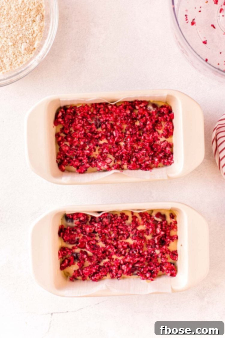 Overhead photo of two loaf pan with cranberry bits on top of the batter.