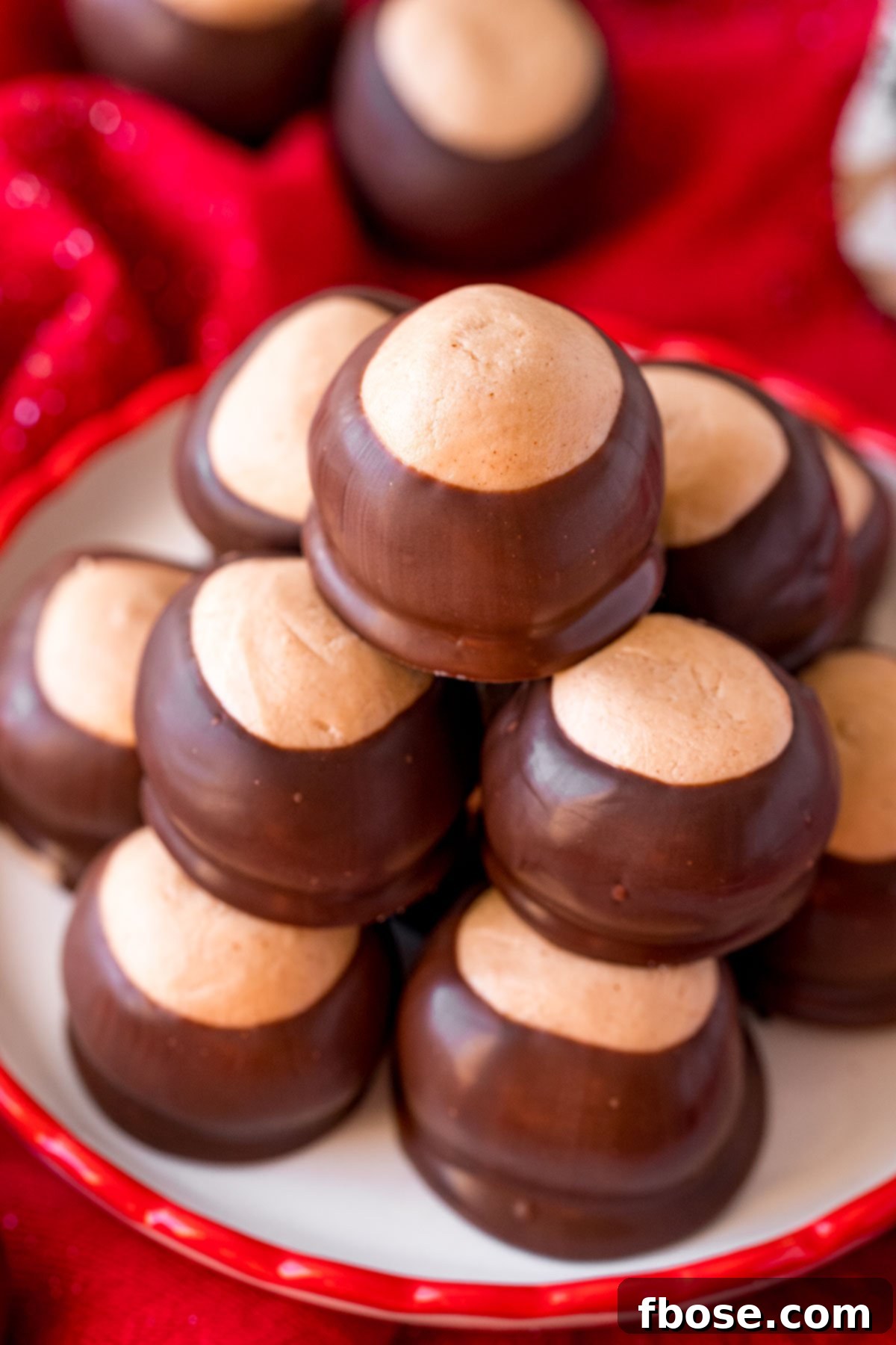 Close up, slightly overhead photo of a plate of buckeyes, showcasing their smooth chocolate coating and a hint of peanut butter filling.