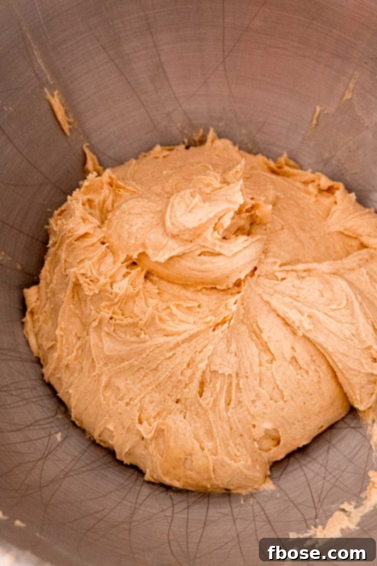Peanut butter, butter, and powdered sugar mixed together to form a creamy base in a metal mixing bowl.
