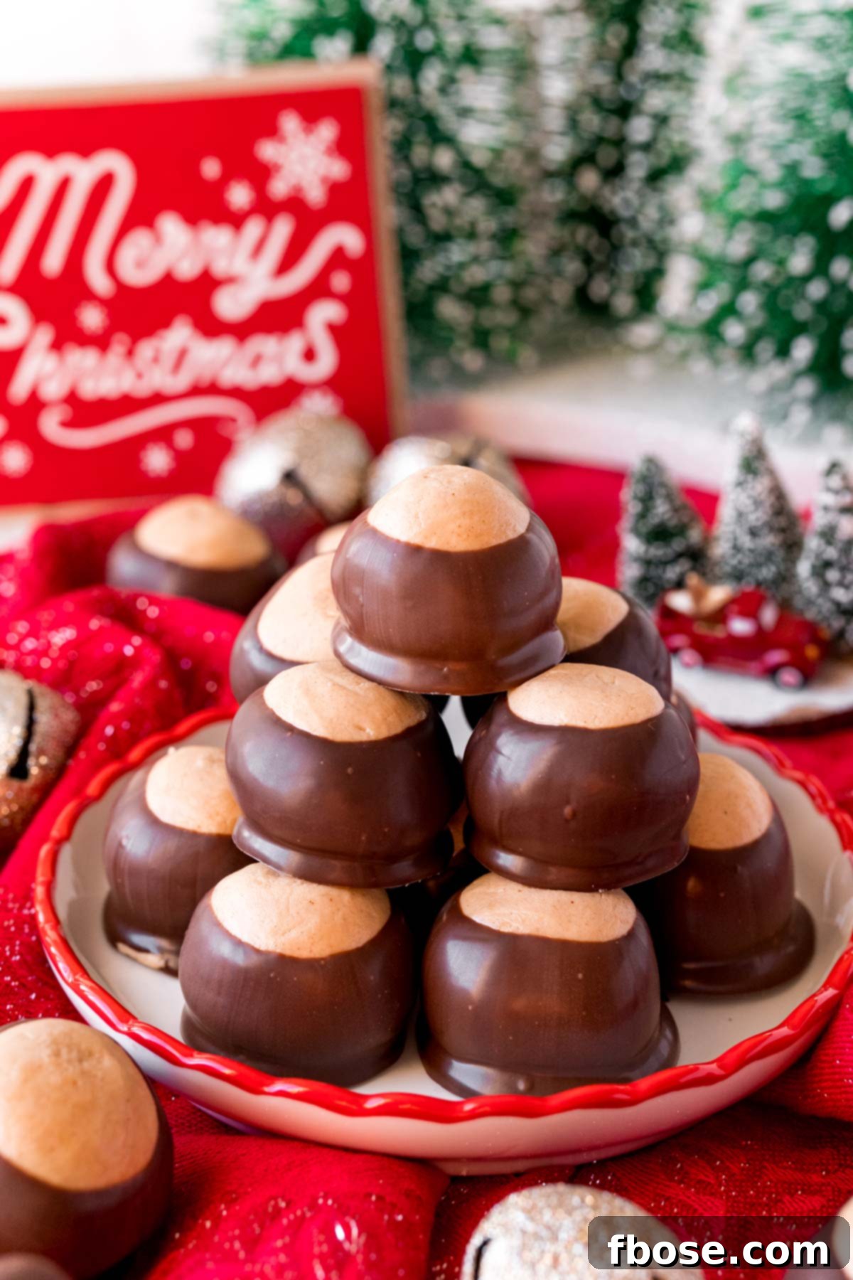A beautifully arranged stack of buckeye candies on a decorative plate, surrounded by charming holiday decorations, ready to be enjoyed.