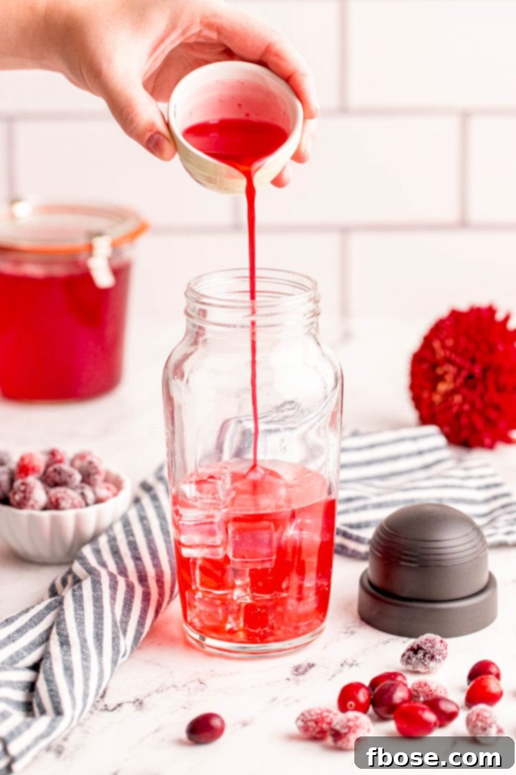 Ruby Red Elixir 7 Cranberry simple syrup being carefully poured into a cocktail shaker, ready to be mixed into a delicious drink.