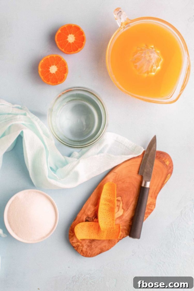 Overhead photo of fresh oranges, water, sugar, and orange peels – the essential ingredients for making orange simple syrup.