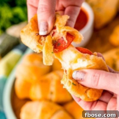 Close up photo of a pizza roll being pulled apart by a woman's hands.