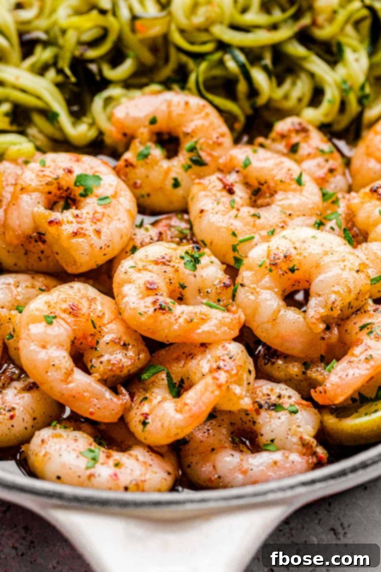 Close up photo of garlic lemon shrimp with zucchini noodles in a skillet, ready to be served, garnished with fresh parsley.