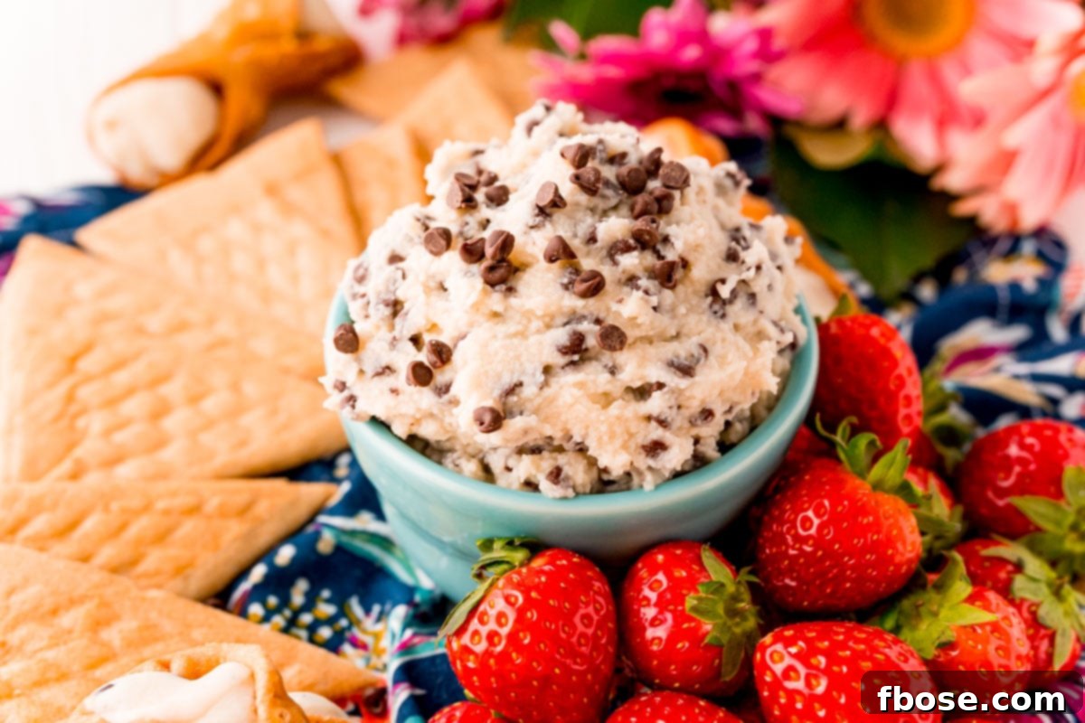 Close up photo of the finished cannoli dip, studded with mini chocolate chips, in a vibrant teal bowl, highlighting its rich and creamy texture.