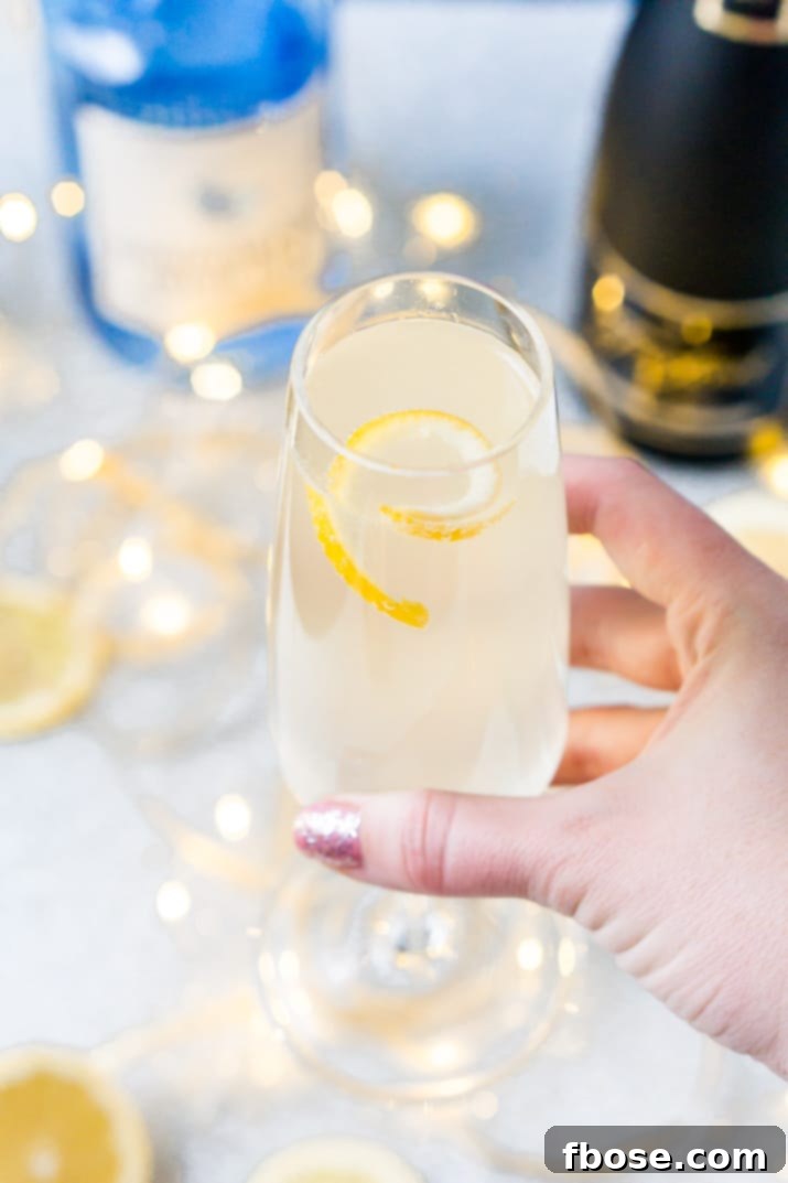 Refreshing French 75 cocktail made with lemon, gin, and champagne, garnished with a lemon twist.