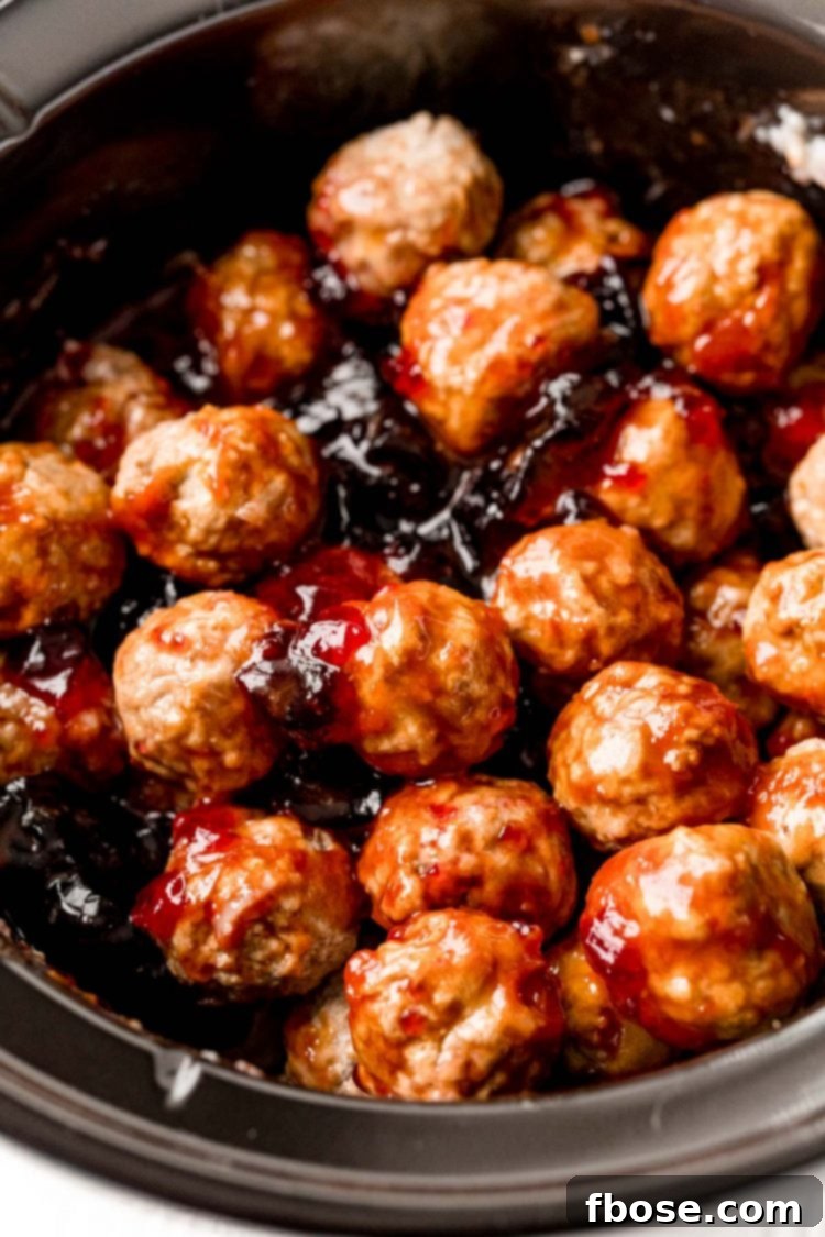 Meatballs coated in grape jelly sauce, simmering in a slow cooker.