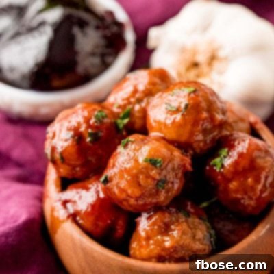 Close up photo of grape jelly meatballs in a brown bowl, garnished with fresh parsley.