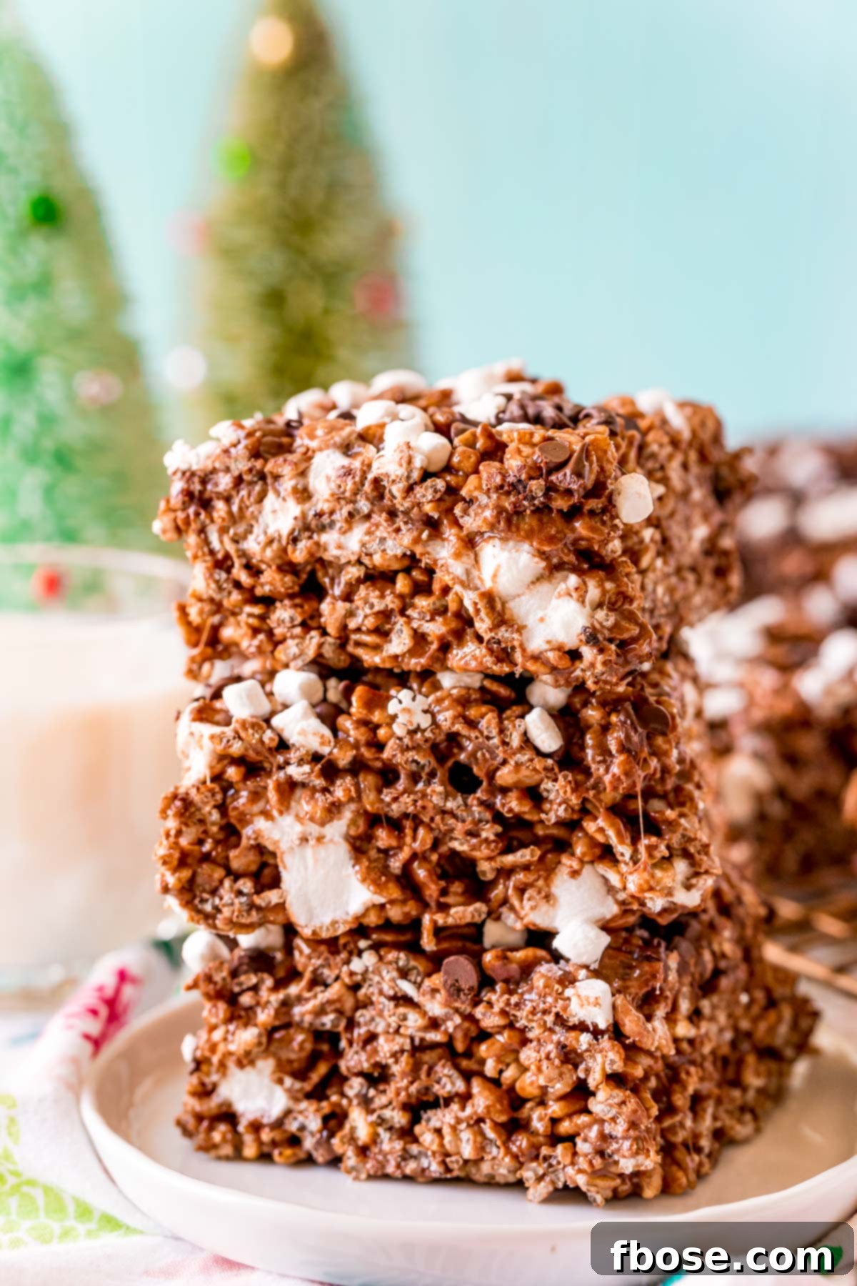 Toasty Cocoa Krispie Bars 2 Close up photo of 3 chocolate rice krispie treats stacked on top of each other on a white plate.